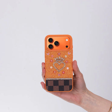 Hand holding a decorated phone case with a heart and crown design on a light gray background