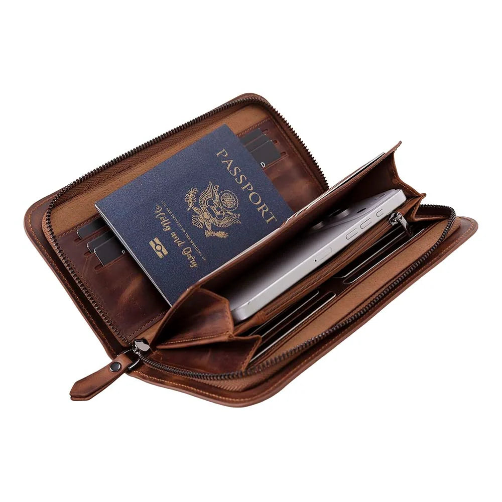A brown leather passport holder and document case shown open, containing a blue passport, a silver tablet, and card slots, on a plain white background.