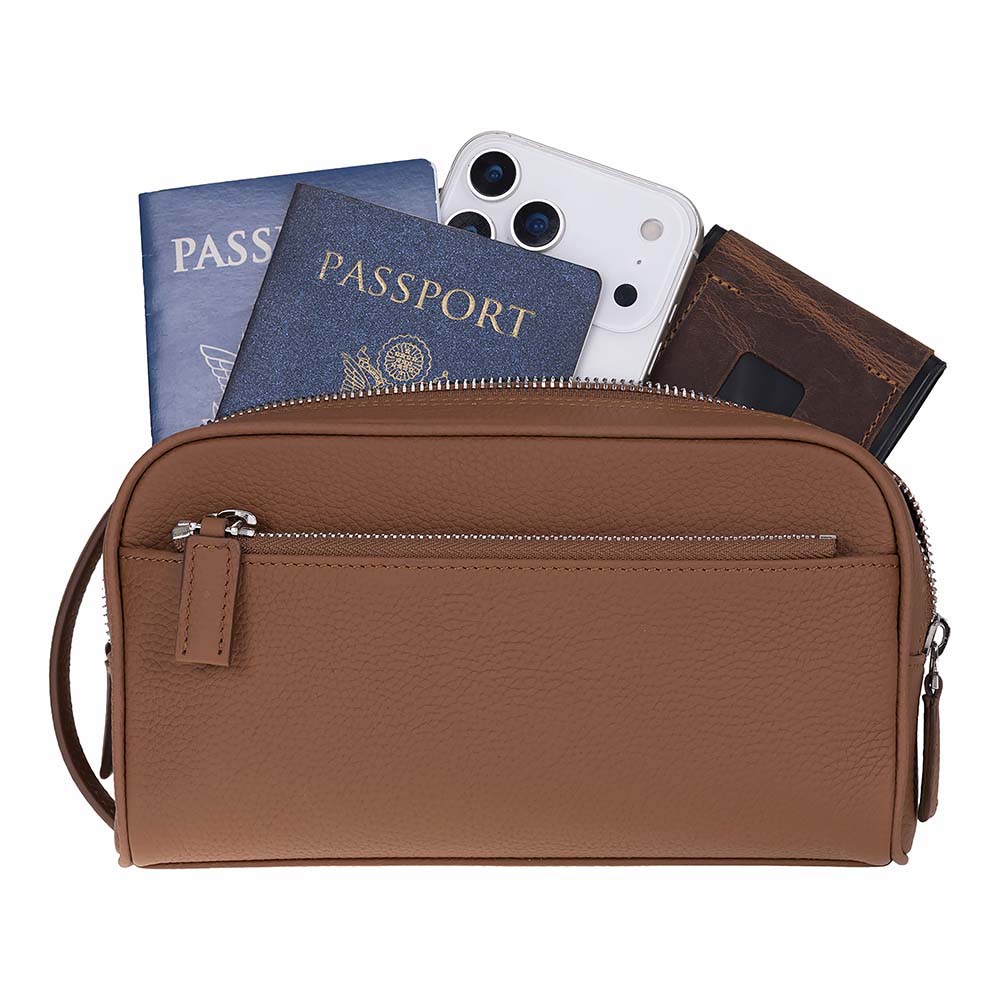 A brown pebbled leather travel pouch with a front zip pocket, shown with passports, a smartphone, and a wallet peeking out from the top on a white background.