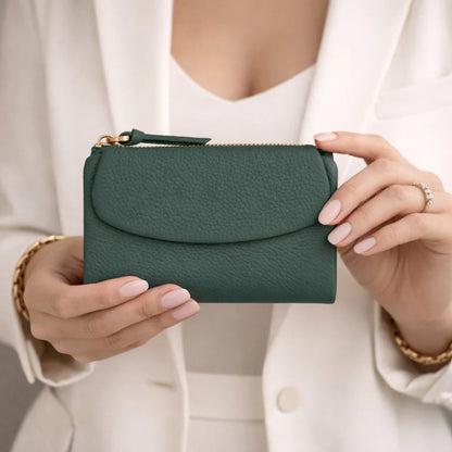 Green wallet held by a person wearing a white outfit